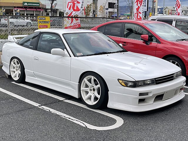 Side view of a Nissan Sileighty parked in a parking space, showcasing its sleek design with custom modifications and sporty stance.