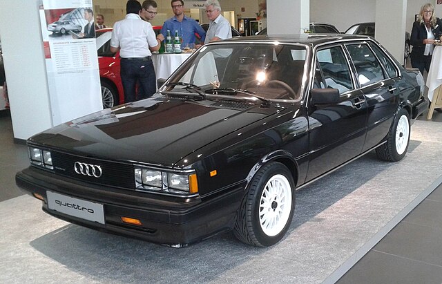 A classic Audi 4000 parked on a scenic road, showcasing its boxy 80s design, quad headlights, and signature Audi grille.