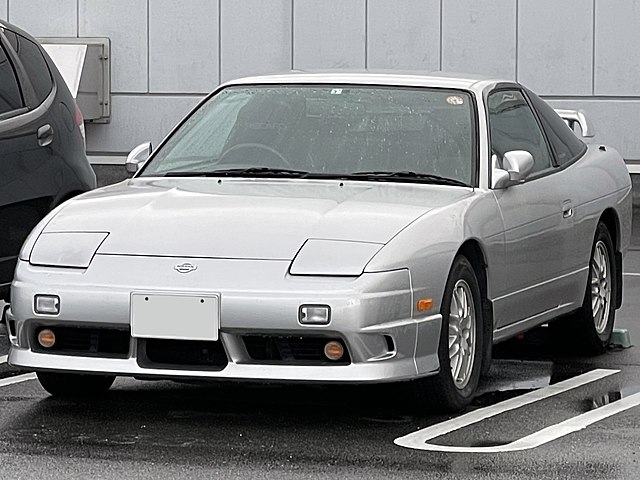 Side view of the Nissan 180SX showcasing its sleek design and pop-up headlights, representing the classic Japanese sports car with its turbocharged engine options.