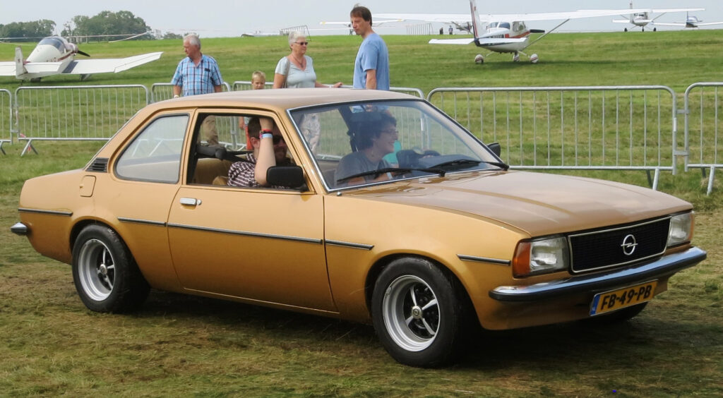 Driver behind the wheel of a brown Opel Ascona B, showcasing its classic interior and vintage design.