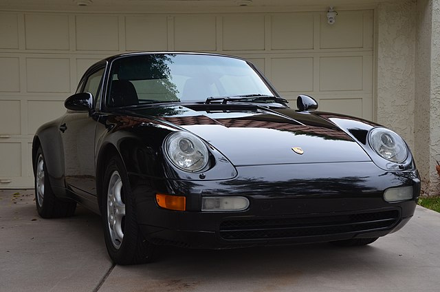 1995 Porsche 911 Turbo parked in front of a sleek garage, showcasing its iconic 90s design and powerful presence.